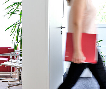 Frau im Büro mit ECOVIS Ordner rot unter dem Arm