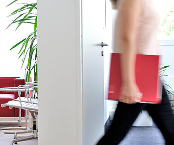 Frau im Büro mit ECOVIS Ordner rot unter dem Arm