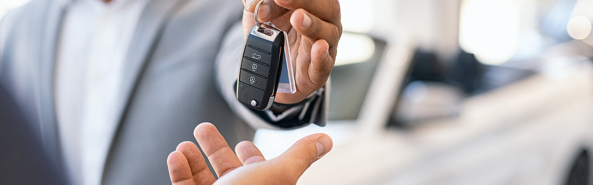 Den Firmenwagen ohne Fahrtenbuch und ohne 1 %-Regelung nutzen – ist das zu schön, um wahr zu sein? Firmenwagen Geschäftsmann Übergabe Autoschlüssel Autohaus